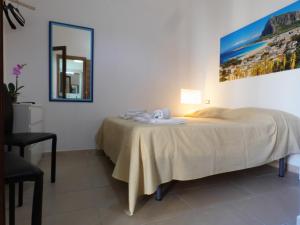 a bedroom with a bed and a mirror and a chair at Appartamenti Leone1 in San Vito lo Capo