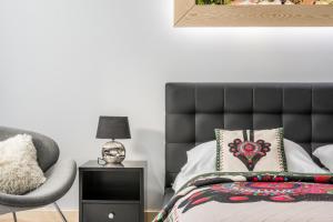 een slaapkamer met een zwart bed en een stoel bij Apartamenty Comfort & Spa Stara Polana VIPAPARTAMENTY in Zakopane