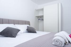 1 dormitorio con cama blanca y almohadas grises en Apartments Sky, en Vodice