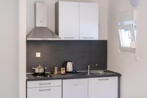 una cocina con armarios blancos y fregadero en Apartments Sky, en Vodice