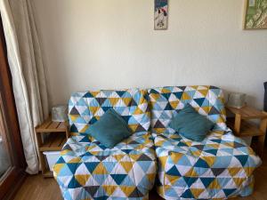 a couch sitting in a living room with a blanket at Studio 22m² balcon Pégase Phenix Le Corbier in Le Corbier