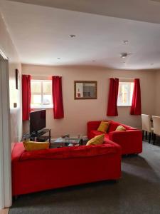 a living room with a red couch and a table at 3 Wood Yard Cottages, Red Mayes Farm in Long Sutton