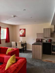 a living room with a red couch and a kitchen at 3 Wood Yard Cottages, Red Mayes Farm in Long Sutton
