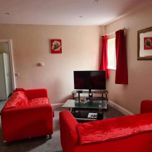 a living room with red furniture and a flat screen tv at 3 Wood Yard Cottages, Red Mayes Farm in Long Sutton