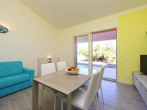 ein Esszimmer mit einem Tisch und einem blauen Sofa in der Unterkunft Holiday Home Baia delle Mimose by Interhome in Valledoria