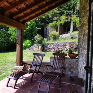 een veranda met 2 stoelen en een stenen muur bij O Lughar Darriba Fogar Natural in Gallardo