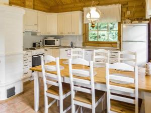 a kitchen with a wooden table and white cabinets at Holiday Home Kuukatti by Interhome in Lahdenperä +28 photos