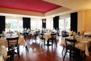 a dining room with many tables and chairs and windows at Ara Classic in Ingolstadt