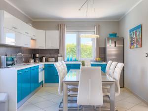 a kitchen with blue cabinets and a table and chairs at Holiday Home Villa Valentina by Interhome in Loborika