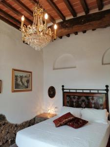 a bedroom with a white bed with a chandelier at Casa L Oliveta in Montemagno