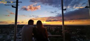 a couple watching the sunset from a building at Baltic Apartments - Platan Tower in Świnoujście