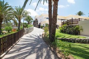 une passerelle devant une maison plantée de palmiers dans l'établissement Grupotel Tres Vidas, à San Agustín