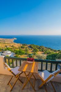 a balcony with a wooden table and chairs and the ocean at Althea Archontika Tis Androu in Batsi