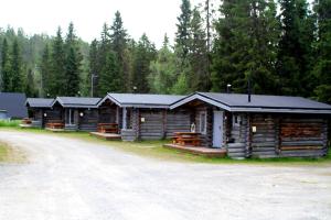 une rangée de cabanes en rondins sur le côté d'un chemin de terre dans l'établissement Mökki Cottages RukaTupa, à Ruka
