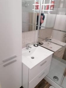 ein weißes Badezimmer mit einem Waschbecken und einem Spiegel in der Unterkunft Studio vue sur la mer au 6ème et dernier étage in Canet-en-Roussillon