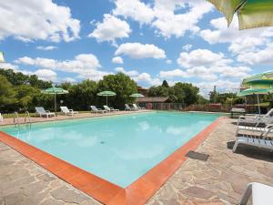 a large swimming pool with chairs and umbrellas at Apartment Il Selleria - TER105 by Interhome in Terricciola