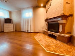 a living room with a fireplace and a wooden floor at Grand Apartment in Nelipyno