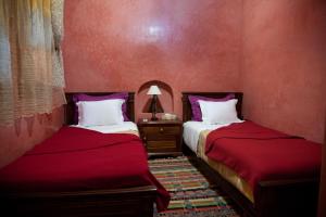 2 Betten in einem Zimmer mit roten Wänden in der Unterkunft Riad Dar Alia in Rabat