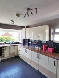 a kitchen with white cabinets and a large window at Fourth Avenue, Lovely bungalow available for guests and contractors Parking wifi in Nottingham