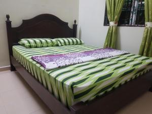 Una cama con sábanas y almohadas verdes y blancas. en Kembara Homestay Lenggong en Kampong Ulu Jepai