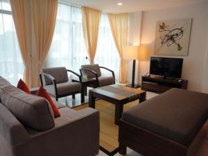a living room with a couch and chairs and a television at Samsuria Beach Apartment Resort in Cherating