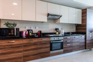 a kitchen with wooden cabinets and a stove top oven at Stella Stays Stylish 1 BDR Dubai JBR Beach Netflix in Dubai