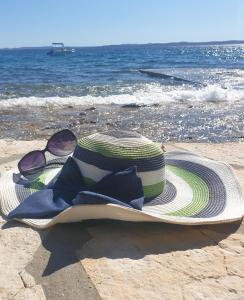 un sombrero de paja y gafas de sol sentadas en una playa en Apartments Anita - Punta Skala, en Petrčane