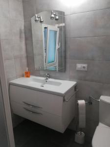 Un baño con lavabo, espejo e inodoro. en PISO XUNQUEIRA, en Viveiro