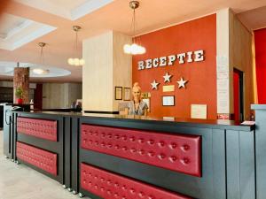 Un uomo in piedi al bancone della reception in un ristorante di Hotel Victoria a Cluj-Napoca