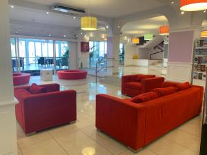 a lobby with red couches in a building at Aparthotel Los Dragos del Sur in Puerto de Santiago