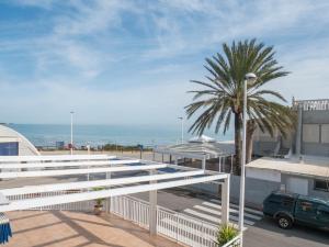 a palm tree and a building with the ocean in the background at Apartamentos Canaret Punta Canaret Marineu Playa Romana in Alcossebre