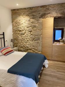 een slaapkamer met een bed en een stenen muur bij Apartamento Casa Xesteira in Poio