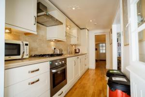 a kitchen with white cabinets and a microwave at Central Courtyard Apartment in Bath