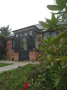 a house with a black front door and some flowers at Comfortable double bedroom lovely bungalow in Manchester