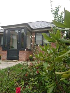 a house with a black door and some flowers at Comfortable double bedroom lovely bungalow in Manchester