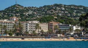 vistas a una playa con palmeras y edificios en Rosamar & Spa 4*s en Lloret de Mar