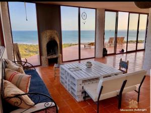 een woonkamer met een tafel en uitzicht op de oceaan bij DAV MAHAL Eco lodge in Sidi Kaouki