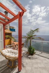 ein Balkon mit Tisch und Stühlen und dem Meer in der Unterkunft maktub sunset cottage in Paul do Mar