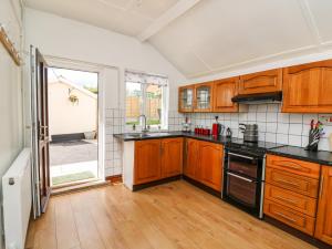 a kitchen with wooden cabinets and a large window at Green Cottage in Rhayader