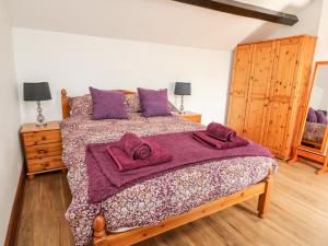 una camera da letto con un letto con coperte e cuscini viola di Green Cottage a Rhayader