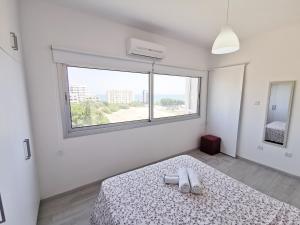 a white bedroom with a bed and a window at Mackenzie Seaview Paradise in Larnaca