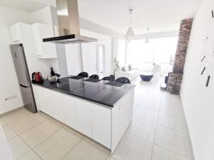 a kitchen with white cabinets and a black counter top at Mackenzie Seaview Paradise in Larnaka