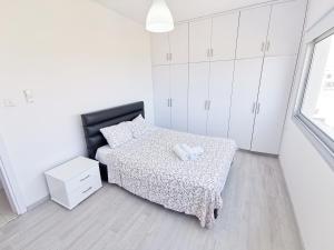 a white bedroom with a bed and white cabinets at Mackenzie Seaview Paradise in Larnaca