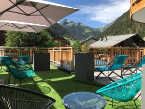 a patio with chairs and tables with mountains in the background at Hôtel Les Ancolies à Arêches in Arêches-Beaufort