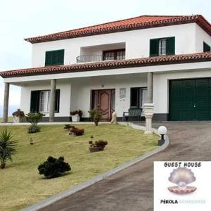 una piccola casa bianca con un garage verde di Pérola Achadense Guesthouse a Achada