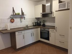 Una cocina con gabinetes blancos y un fregadero. en Ferienwohnung Katrin, en Kelberg