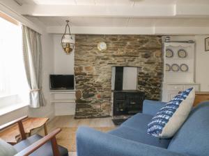 a living room with a blue couch and a stone wall at Waves End in Port Isaac