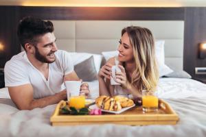 a man and woman sitting in bed with a tray of food at New Work Hotel Essen in Essen