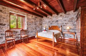 a bedroom with a bed and a stone wall at Seixal Sunny Villa A & B by Amazing Madeira in Seixal
