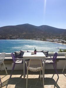 einen Tisch und Stühle auf einem Balkon mit Blick auf das Wasser in der Unterkunft Niriedes Hotel in Platis Gialos Sifnos